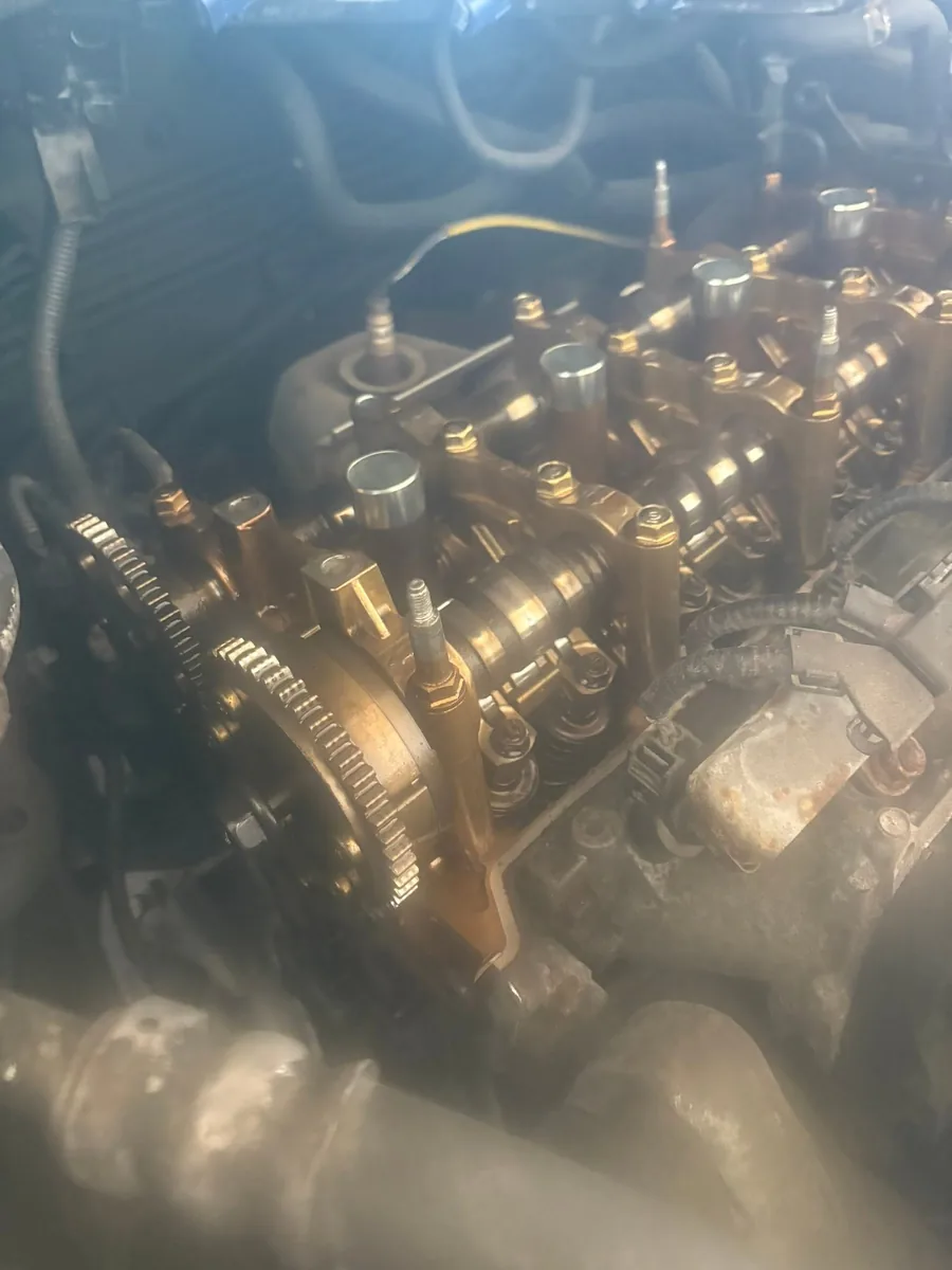 Close-up of a cylinder head with the camshafts and valve train exposed and wet with oil, at AutoNorth Auto Repair in North Bay