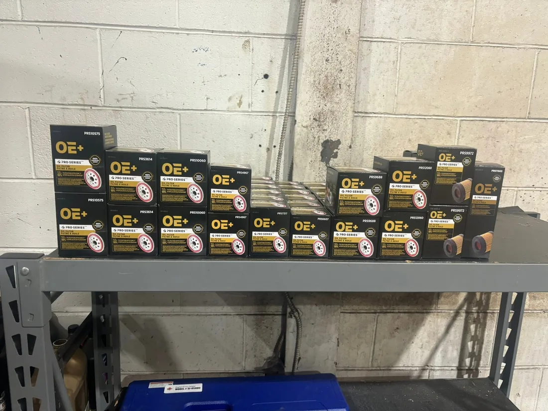 Boxed OE Plus Pro-Series oil filters lined up on a grey steel shelf against a painted block wall at AutoNorth Auto Repair in North Bay