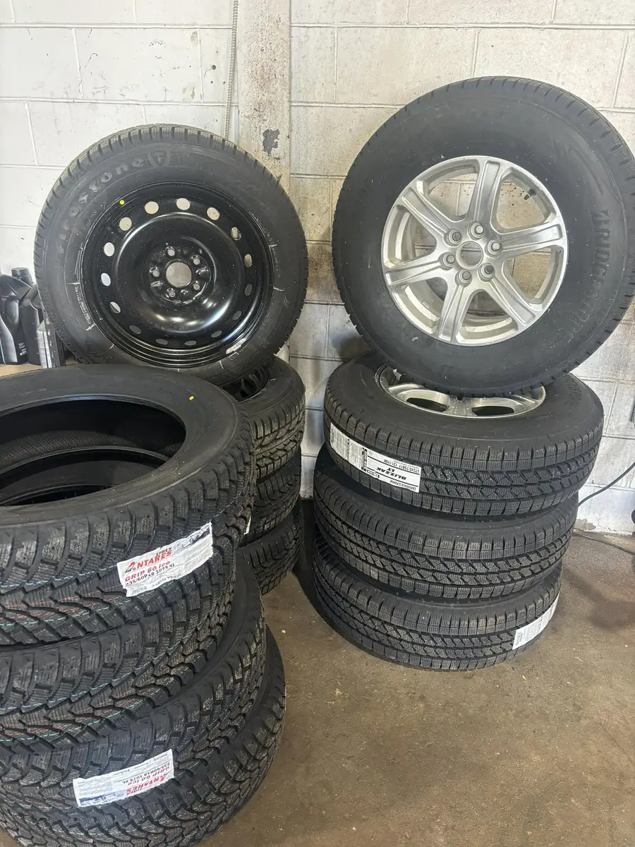 Winter tires mounted on both steel and alloy rims stacked at AutoNorth Auto Repair in North Bay