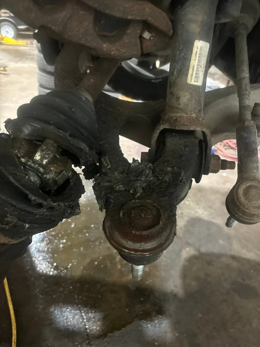 Underside view of a greasy worn suspension joint and torn boot on a vehicle at AutoNorth in North Bay